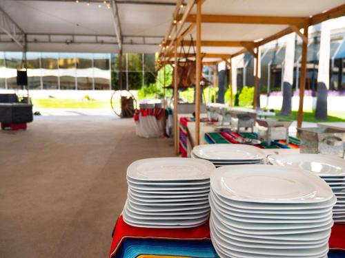 a stack of white plates sitting on top of a table at MS Milenium Monterrey Curio Collection by Hilton in Monterrey