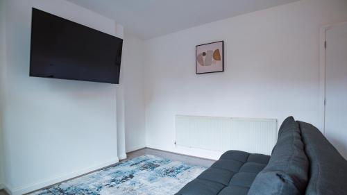 a living room with a couch and a flat screen tv at ALTIDO Charming 3-bed house in Walsall in Bescot