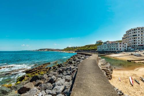 einen Strand mit Felsen und Gebäuden und dem Meer in der Unterkunft Villa Martha - Appt 01 in Guéthary