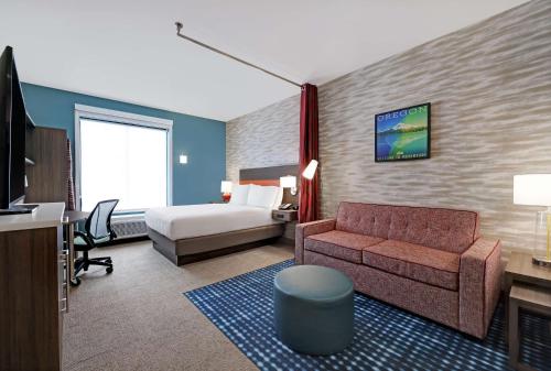 Home2 Suites By Hilton Salem في سالم: غرفه فندقيه بسرير واريكه