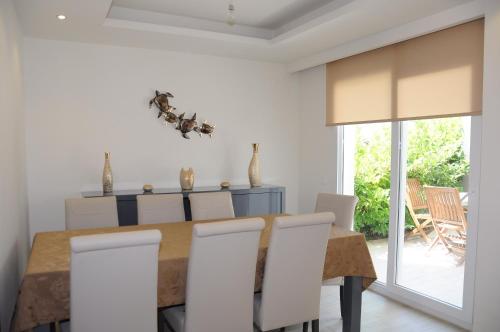 a dining room with a wooden table and white chairs at Exclusive Villas in Kusadası