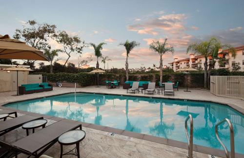 una piscina con mesas y sillas en un complejo en Redondo Beach Hotel, Tapestry Collection by Hilton en Redondo Beach