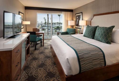 レドンドビーチにあるRedondo Beach Hotel, Tapestry Collection by Hiltonのベッド、デスク、テレビが備わるホテルルームです。