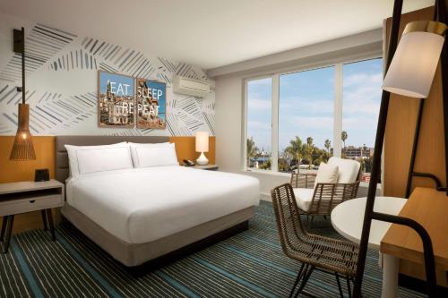 サンディエゴにあるThe Monsaraz San Diego, Tapestry Collection By Hiltonのベッド、デスク、椅子が備わるホテルルームです。