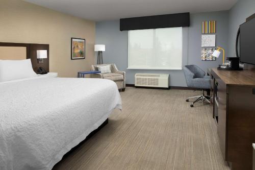 Warroad的住宿－Hampton Inn Warroad, MN，配有一张床和一把椅子的酒店客房