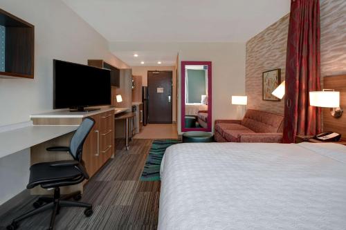 a hotel room with a bed and a desk with a television at Home2 Suites By Hilton Kalamazoo Downtown, Mi in Kalamazoo