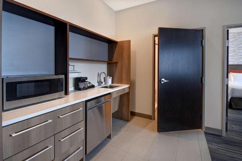 a small kitchen with a microwave and a sink at Home2 Suites By Hilton Kalamazoo Downtown, Mi in Kalamazoo