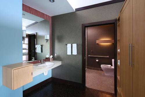 y baño con lavabo, aseo y espejo. en Tulyp, Tapestry Collection by Hilton, en Holland