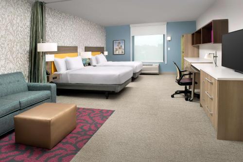 Home2 Suites by Hilton Orlando Downtown, FL في أورلاندو: غرفة فندقية بسريرين ومكتب