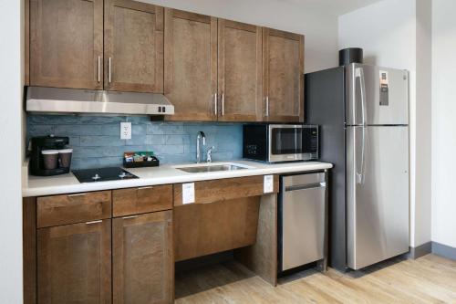 a kitchen with wooden cabinets and a stainless steel refrigerator at Homewood Suites By Hilton Dillon in Dillon
