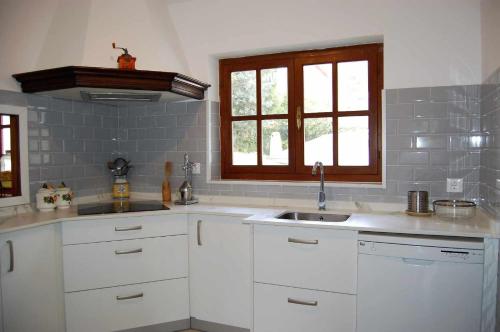 eine Küche mit weißen Schränken, einem Waschbecken und einem Fenster in der Unterkunft Casa Vaqueiro Llanes in Llanes