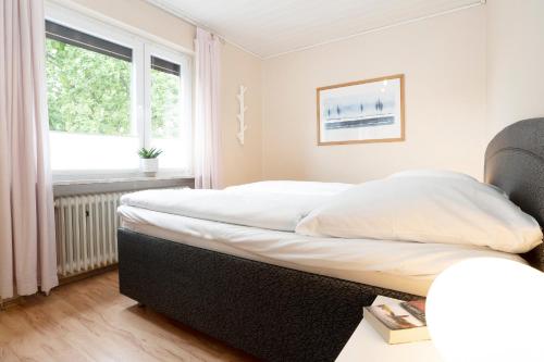 um quarto com uma grande cama branca e uma janela em Haus Sonneninsel Wohnung 5 em Grömitz