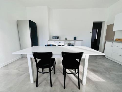 - une table blanche avec quatre chaises dans la cuisine dans l'établissement Spacieux et Lumineux, à Saint-Claude