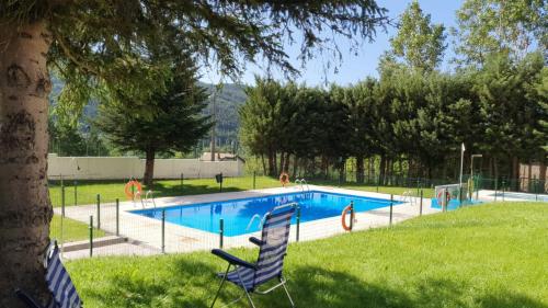 a swimming pool in a park with two chairs in the grass at Rincón de Líerde in Villanúa