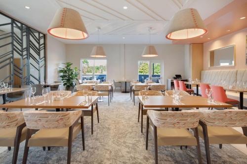 a dining room with tables and chairs and windows at Hilton Garden Inn Panama City Airport, Fl in Panama City