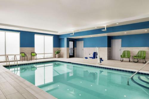 Hampton Inn & Suites Olean, Ny في أوليان: مسبح بجدران زرقاء وكراسي خضراء