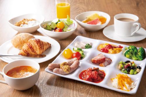 a table with plates of food and cups of coffee at The Royal Park Hotel Tokyo Haneda Airport Terminal 3 in Tokyo