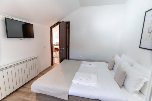 ein weißes Bett in einem Zimmer mit einem Flachbild-TV in der Unterkunft RoofTop in Aranđelovac
