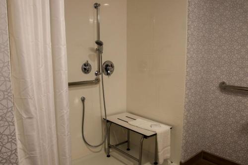 a bathroom with a shower with a table and a shower curtain at Hampton Inn & Suites Olean, Ny in Olean