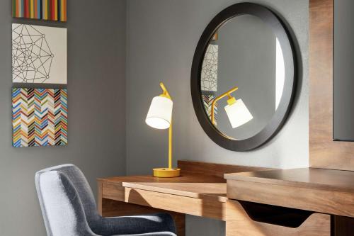 a room with a desk with a mirror and a chair at Hampton Inn & Suites Olean, Ny in Olean
