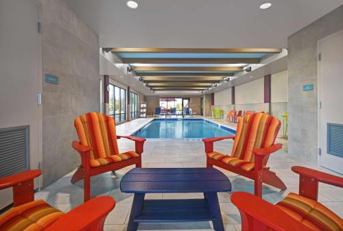 a swimming pool with two chairs and a table and a tablektop at Home2 Suites by Hilton Blacksburg University in Blacksburg