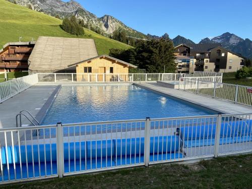 une grande piscine entourée d'une clôture blanche. dans l'établissement Appartement de 2 chambres a Manigod a 100 m des pistes avec piscine partagee et wifi, à Manigod