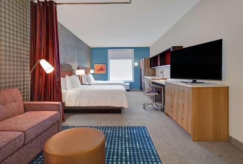 a hotel room with a bed and a flat screen tv at Home2 Suites by Hilton Blacksburg University in Blacksburg