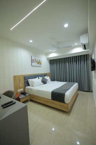 a bedroom with a large bed and a desk at Hotel Shayan Inn in Rajkot
