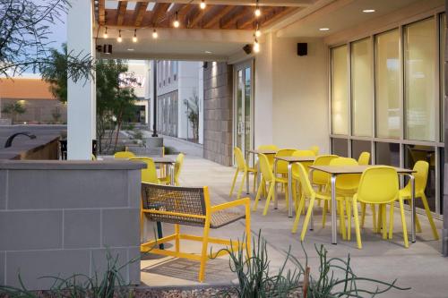 a restaurant with yellow chairs and tables on a patio at Home2 Suites By Hilton Phoenix Avondale, Az in Avondale