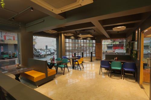 a restaurant with colorful chairs and tables and windows at Hotel Shayan Inn in Rajkot