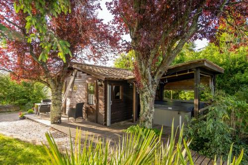 a small wooden shed with a tree in a garden at Le Bassin du Tertre in Fronsac