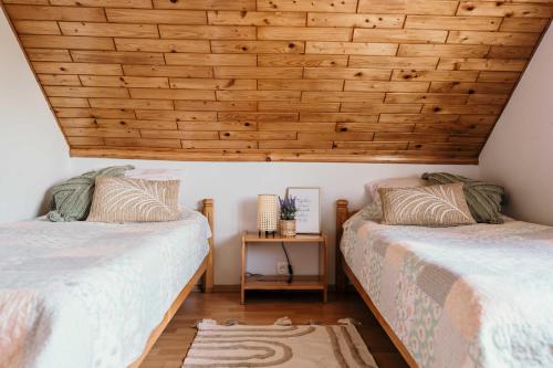 two beds in a room with wooden ceilings at Pokoje Discovery Mazury in Mrągowo