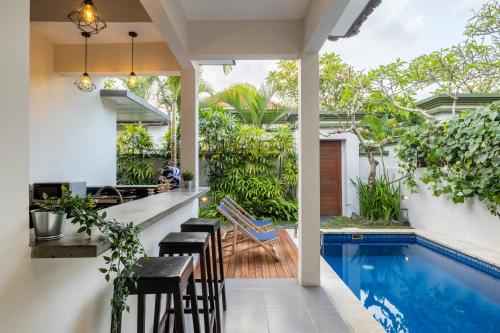 an outdoor bar with stools and a swimming pool in a house at Villa Kisaraa - Kerobokan x Seminyak x Canggu in Kerobokan