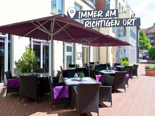 ブーフホルツ・イン・デア・ノートハイデにあるACHAT Hotel Buchholz Hamburgの屋外レストラン(テーブル、パラソルの下の椅子付)