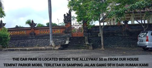 un coche aparcado frente a una pared de piedra en Coliving Bali SWEET HOME Kost Lengkap di Tabanan Kota, en Tabanan