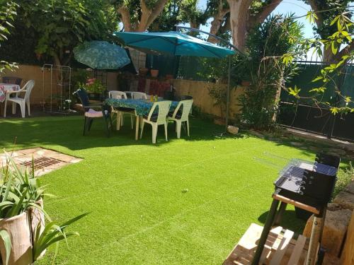 a yard with a table and a blue umbrella at Maison au Pied du Pont du Gard in Remoulins