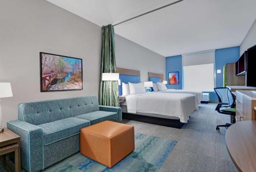 een hotelkamer met een bank en een bed bij Home2 Suites By Hilton Bentonville Rogers in Bentonville