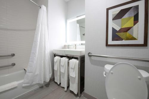 y baño con aseo blanco y lavamanos. en Doubletree Sulphur Lake Charles en Sulphur