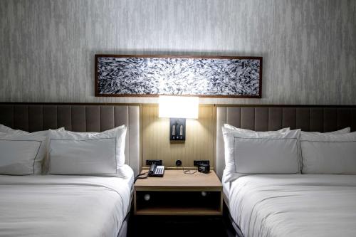 two beds in a hotel room with a table between them at Doubletree Sulphur Lake Charles in Sulphur