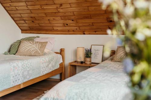 2 Betten in einem Zimmer mit Holzdecken in der Unterkunft Pokoje Discovery Mazury in Mrągowo