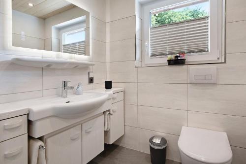 a white bathroom with a sink and a toilet at Haus Fritz in Wittenschwand