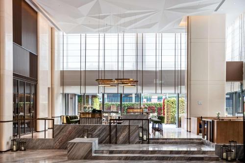 a lobby with a table and chairs in a building at The Mercury Garden Shenzhen Nanshan, A Tribute Portfolio Hotel in Shenzhen