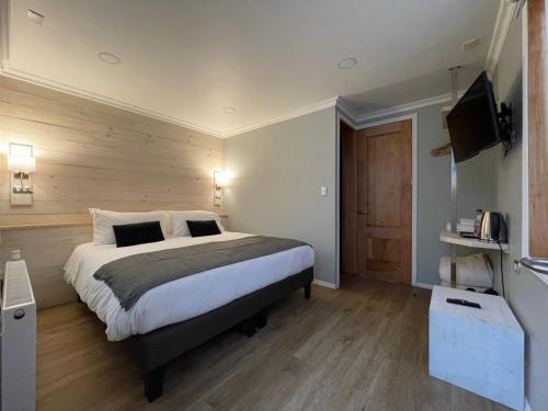 a bedroom with a large bed and a flat screen tv at Hostal Boutique Puerta Roja in Punta Arenas