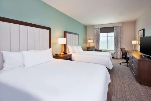 a hotel room with two beds and a flat screen tv at Homewood Suites By Hilton Columbus Easton, Oh in Columbus