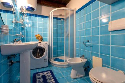 Baño de azulejos azules con lavadora junto a un aseo en Apartment Cavour, en Alghero