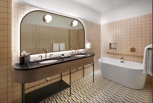 a bathroom with two sinks and a tub and a mirror at The Westley Calgary Downtown, Tapestry Collection By Hilton in Calgary