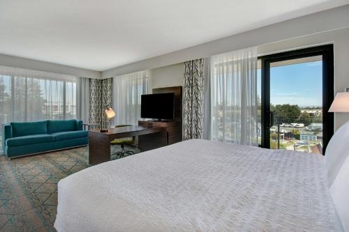 a hotel room with a bed and a couch and a television at Hampton Inn & Suites Sunnyvale-Silicon Valley, Ca in Sunnyvale