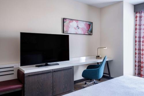 a hotel room with a desk with a television and a chair at Hilton Garden Inn Chino Hills Pomona CA in Pomona