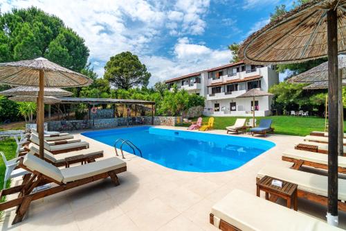 a pool with chairs and umbrellas next to a building at Margi House in Skiathos