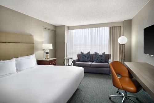 a hotel room with a large bed and a couch at Hilton Richardson Dallas, TX in Richardson